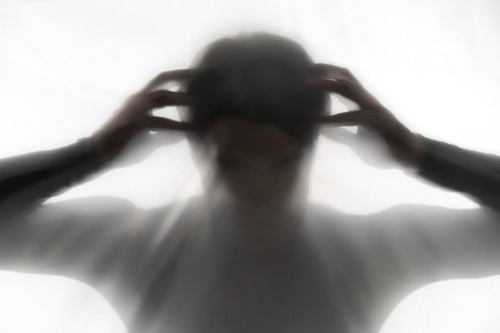 Silueta unei persoane cu trăsături îngrijorate, simbolizând anxietate și tulburări emoționale, vizibilă prin postură și poziția mâinilor la nivelul capului.