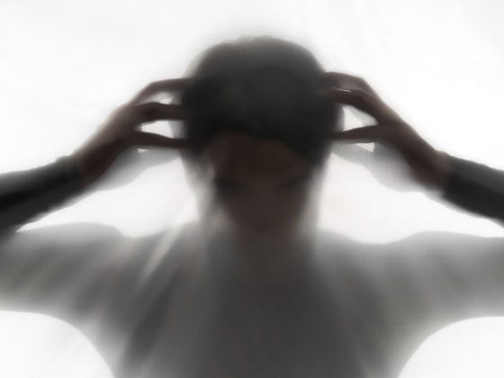 Silueta unei persoane cu trăsături îngrijorate, simbolizând anxietate și tulburări emoționale, vizibilă prin postură și poziția mâinilor la nivelul capului.